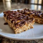 Close-up of homemade protein bars made with oats, topped with melted chocolate drizzle.