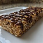 Close-up of a homemade protein bar made with oats and drizzled with melted chocolate.