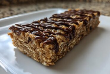 Close-up of a homemade protein bar made with oats and drizzled with melted chocolate.