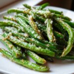 Close-up of bright green beans tossed with garlic and grated cheese, ready to serve.