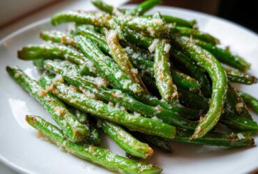 Close-up of bright green beans tossed with garlic and grated cheese, ready to serve.