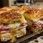 Close-up of freshly baked Ham and Cheese Sliders with melted cheese and poppy seed topping.