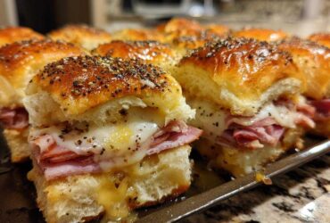Close-up of freshly baked Ham and Cheese Sliders with melted cheese and poppy seed topping.