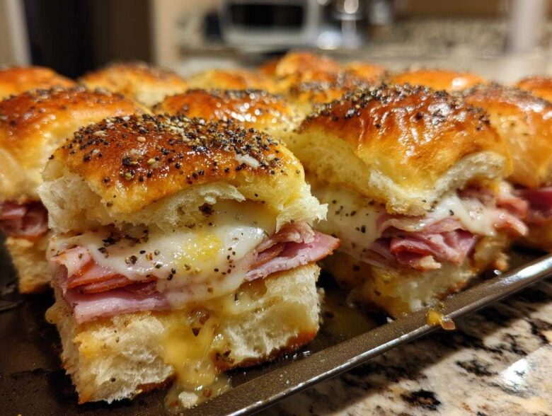 Close-up of freshly baked Ham and Cheese Sliders with melted cheese and poppy seed topping.