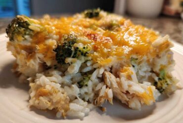 Close-up of a generous serving of chicken broccoli rice casserole topped with melted, slightly browned cheddar cheese.