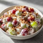 Close-up of creamy chicken salad chick grape salad mixture with red and green grapes and brown sugar topping.