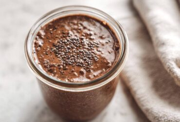 Overhead close-up of rich chocolate overnight oats in a glass jar, topped with a sprinkle of chia seeds.