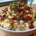 A bowl overflowing with creamy Million Dollar Dip, generously topped with crispy bacon pieces and fresh green onions.