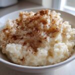 Close-up of a bowl of creamy rice pudding generously sprinkled with ground cinnamon.