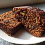 Two thick slices of rich, moist date nut bread showing visible pieces of dates and nuts.