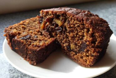 Two thick slices of rich, moist date nut bread showing visible pieces of dates and nuts.