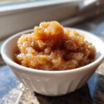 A close-up of chunky, homemade applesauce seasoned with cinnamon in a small white bowl.