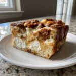 A thick, square slice of overnight french toast casserole with cream cheese filling and cinnamon streusel topping.