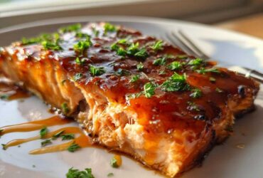 Close-up of a perfectly cooked honey garlic salmon fillet, glistening with glaze and topped with fresh parsley.