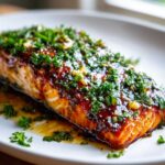 Close-up of a perfectly cooked honey garlic salmon fillet, glazed and topped generously with fresh chopped parsley.