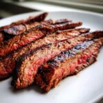 Close-up of medium-rare steak slices showing char marks from grilling, achieved with the carne asada marinade.