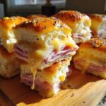 Close-up of Ham and Cheese Sliders with melted cheese dripping over layers of ham.
