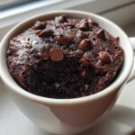 Close-up of a moist chocolate chip mug cake baked in a white mug, ready to eat.