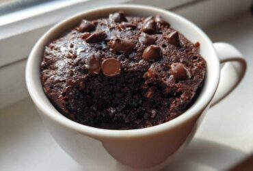 Close-up of a moist chocolate chip mug cake baked in a white mug, ready to eat.
