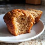 Close-up showing the moist, textured crumb of a honey bran muffin with a bite taken out.
