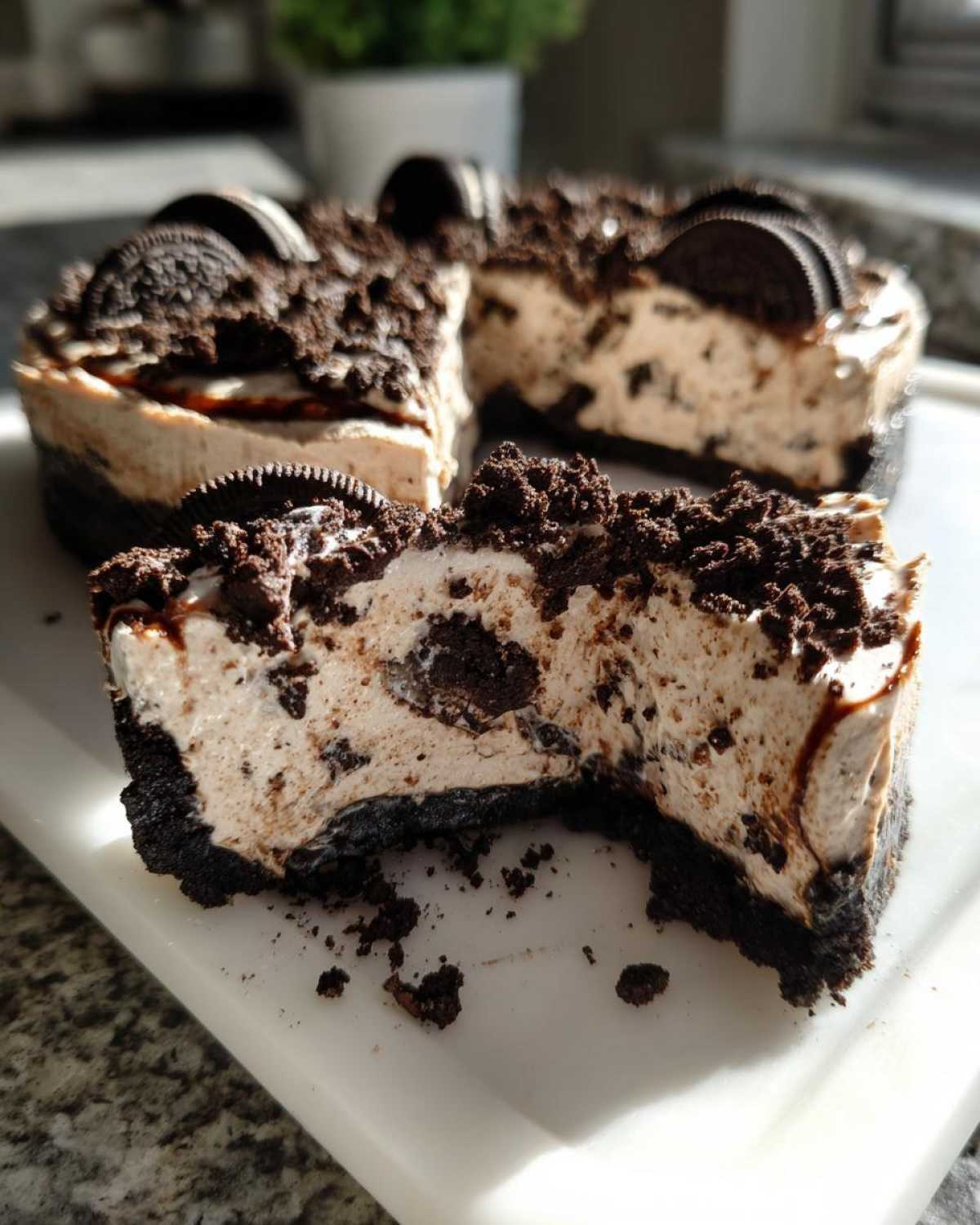 A close-up of a slice of no-bake Oreo pie showing the creamy filling, dark crust, and chocolate drizzle.