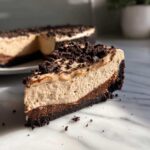 A close-up slice of no-bake Oreo pie showing a dark crust, chocolate layer, and light mousse filling topped with cookie crumbs.