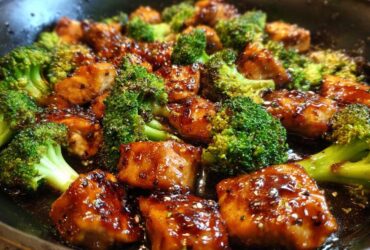 Close-up of glazed chicken pieces mixed with bright green broccoli florets in a dark sauce, showcasing the chicken and broccoli dish.