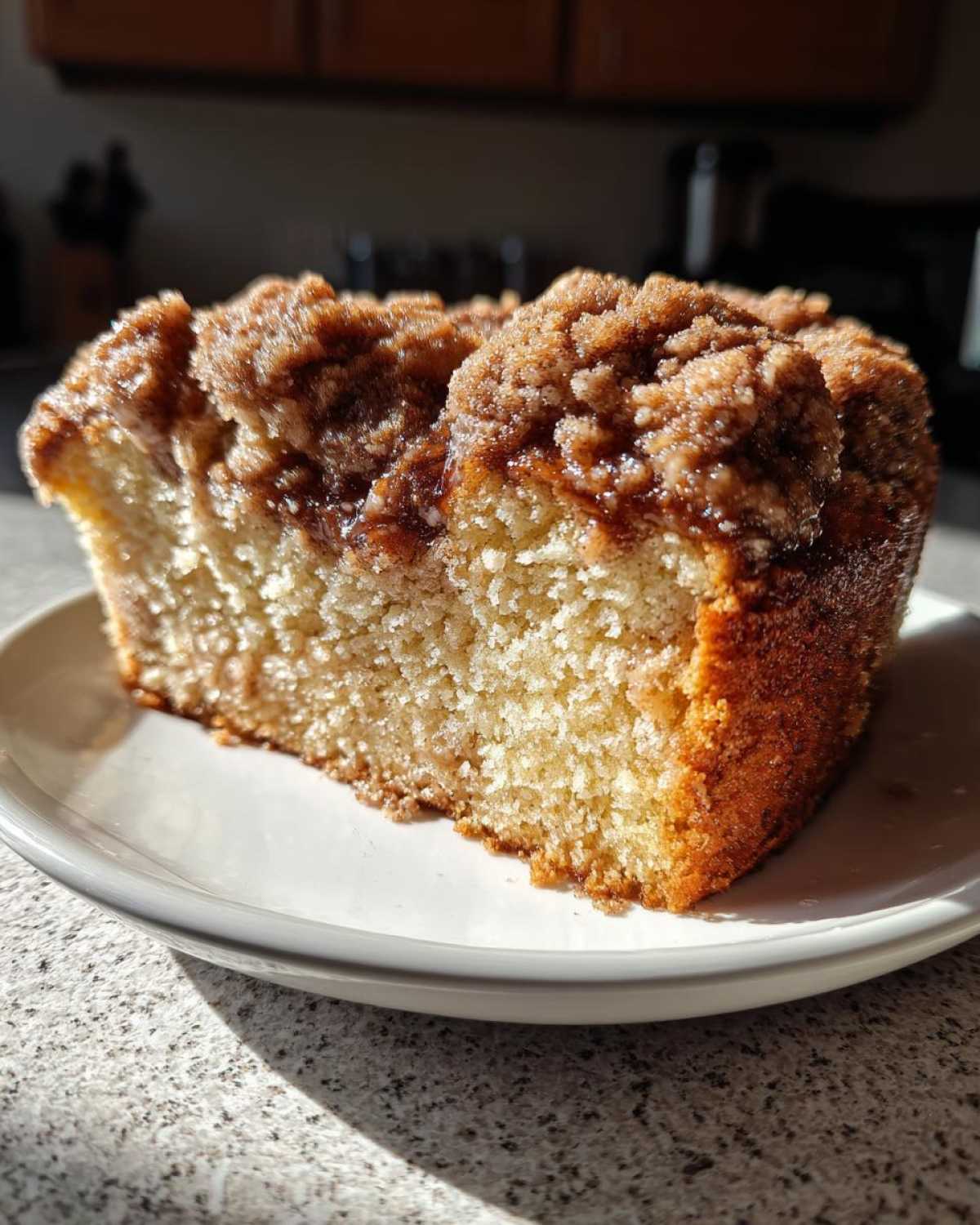 Close-up of a moist slice of coffee cake featuring a thick, sugary cinnamon crumb topping.