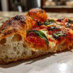 Close-up cross-section showing the airy, open crumb structure of a pizza made with sourdough discard pizza dough.