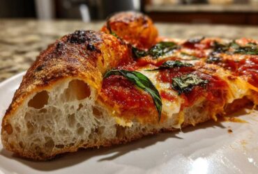 Close-up cross-section showing the airy, open crumb structure of a pizza made with sourdough discard pizza dough.