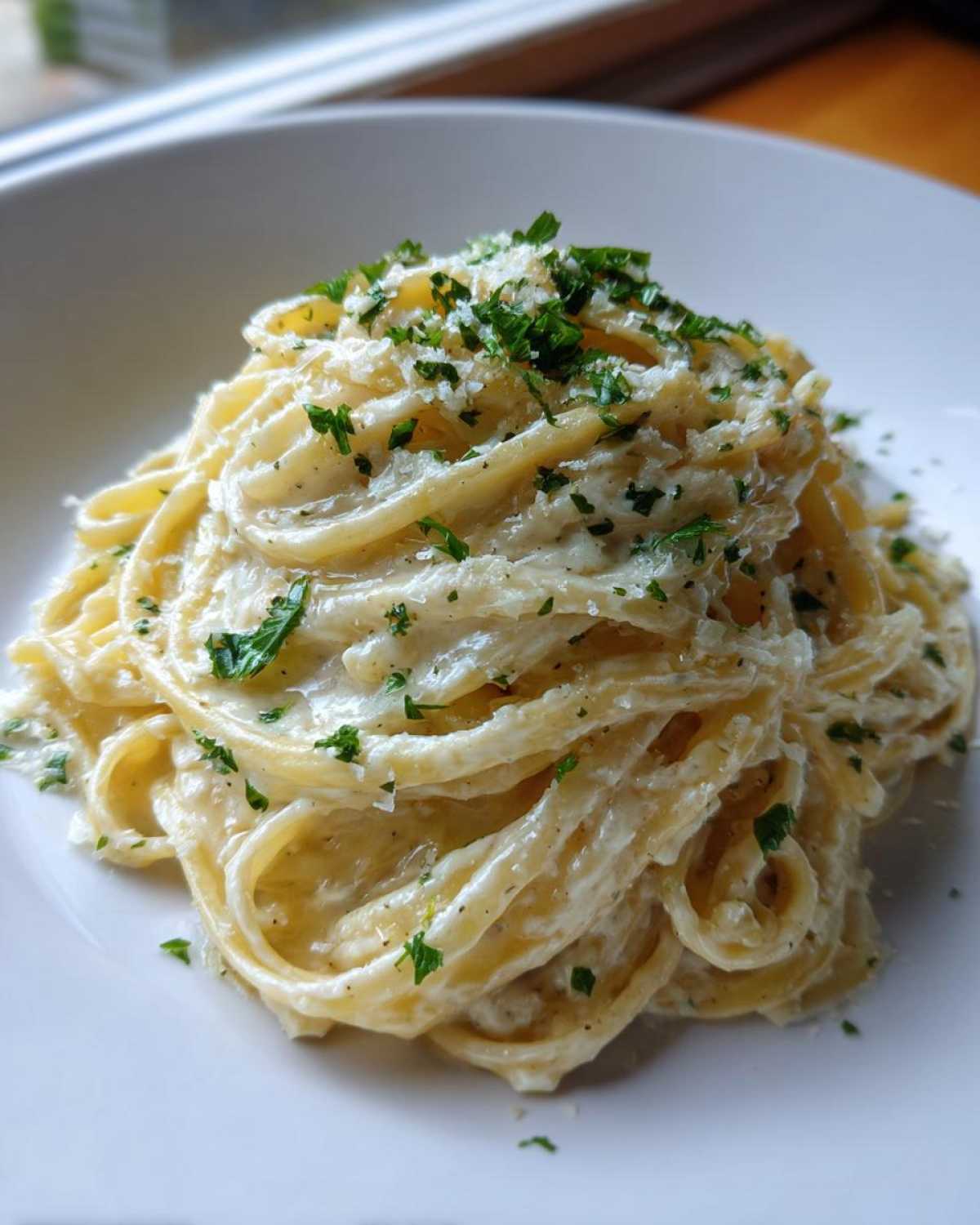 A close-up of creamy fettuccine pasta coated in a rich sauce, topped with grated cheese and fresh parsley, highlighting the garlic parmesan flavor.