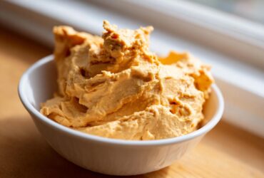 A close-up shot of creamy, orange pumpkin fluff dessert served in a small white bowl.