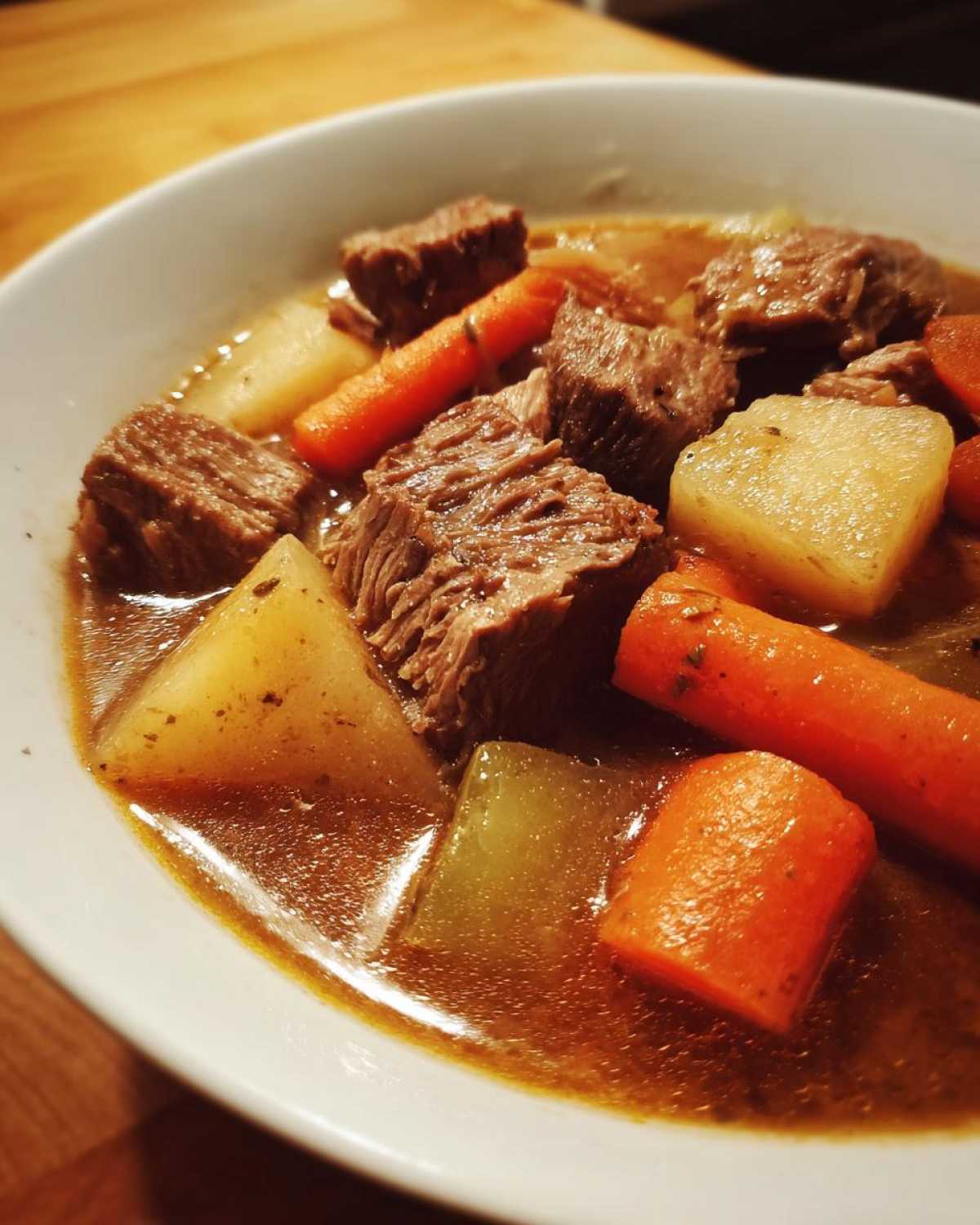 Close-up of tender meat chunks, carrots, and potatoes in a rich broth of the amazing 1-Pot pork stew.