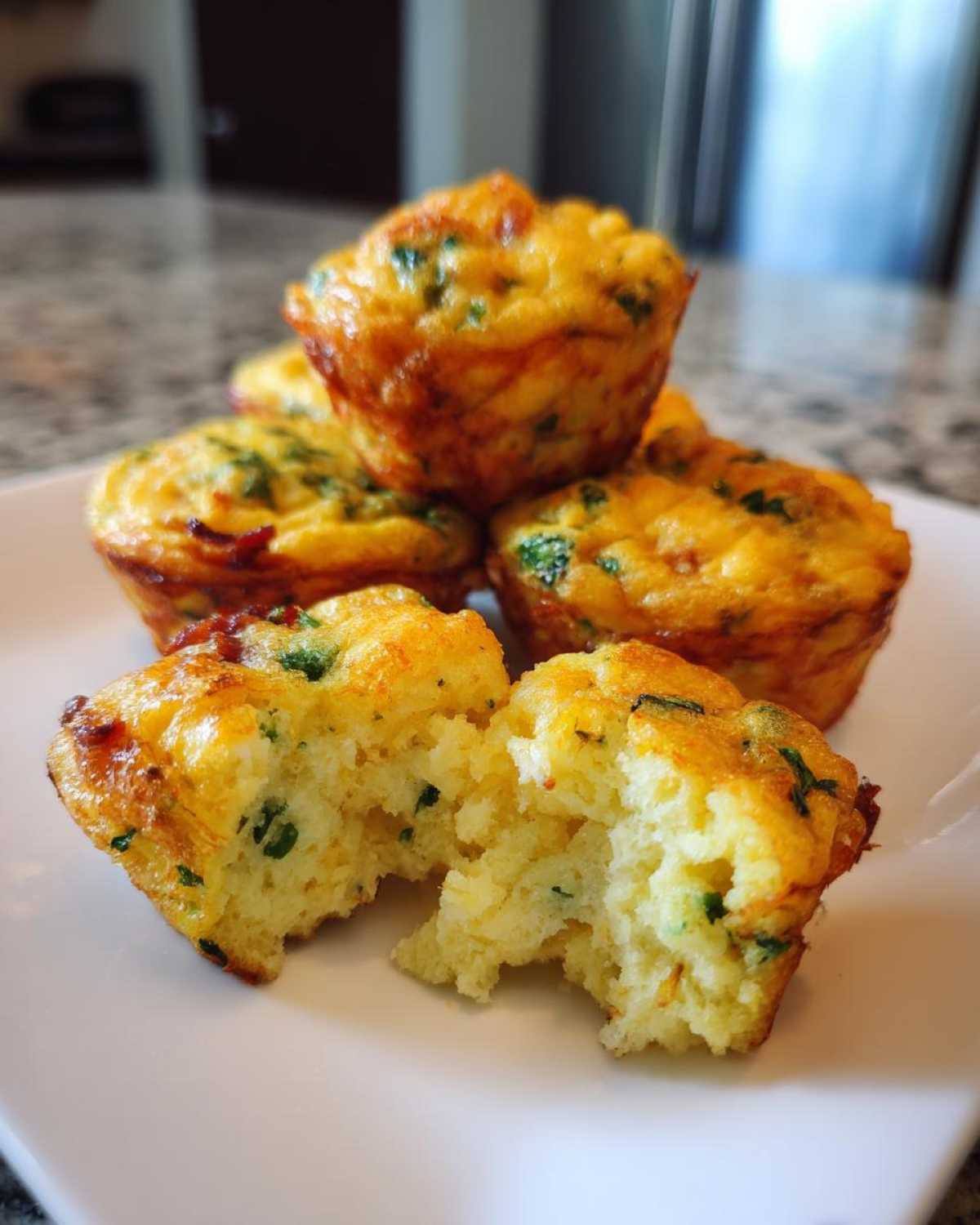 A stack of golden brown, fluffy homemade egg bites, one broken open to show the texture.