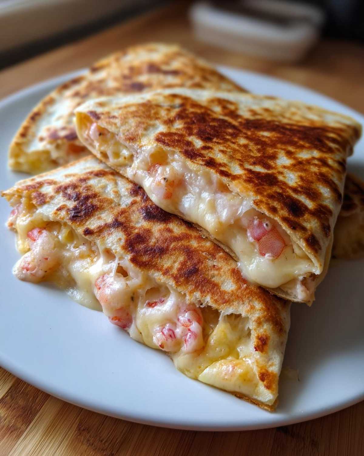 Close-up of golden-brown, grilled shrimp quesadilla wedges oozing with melted cheese and pink shrimp pieces.