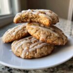A stack of four soft apple pie cookies drizzled with white icing, one cookie on top is broken open.