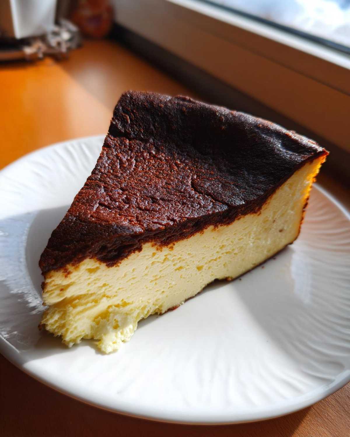 A perfect slice of Basque burnt cheesecake showing its creamy interior and signature dark, caramelized top.