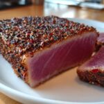 Close-up of a thick, perfectly seared Blackened Tuna Steak, showing a deep red, rare center and a thick spice crust.