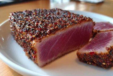 Close-up of a thick, perfectly seared Blackened Tuna Steak, showing a deep red, rare center and a thick spice crust.