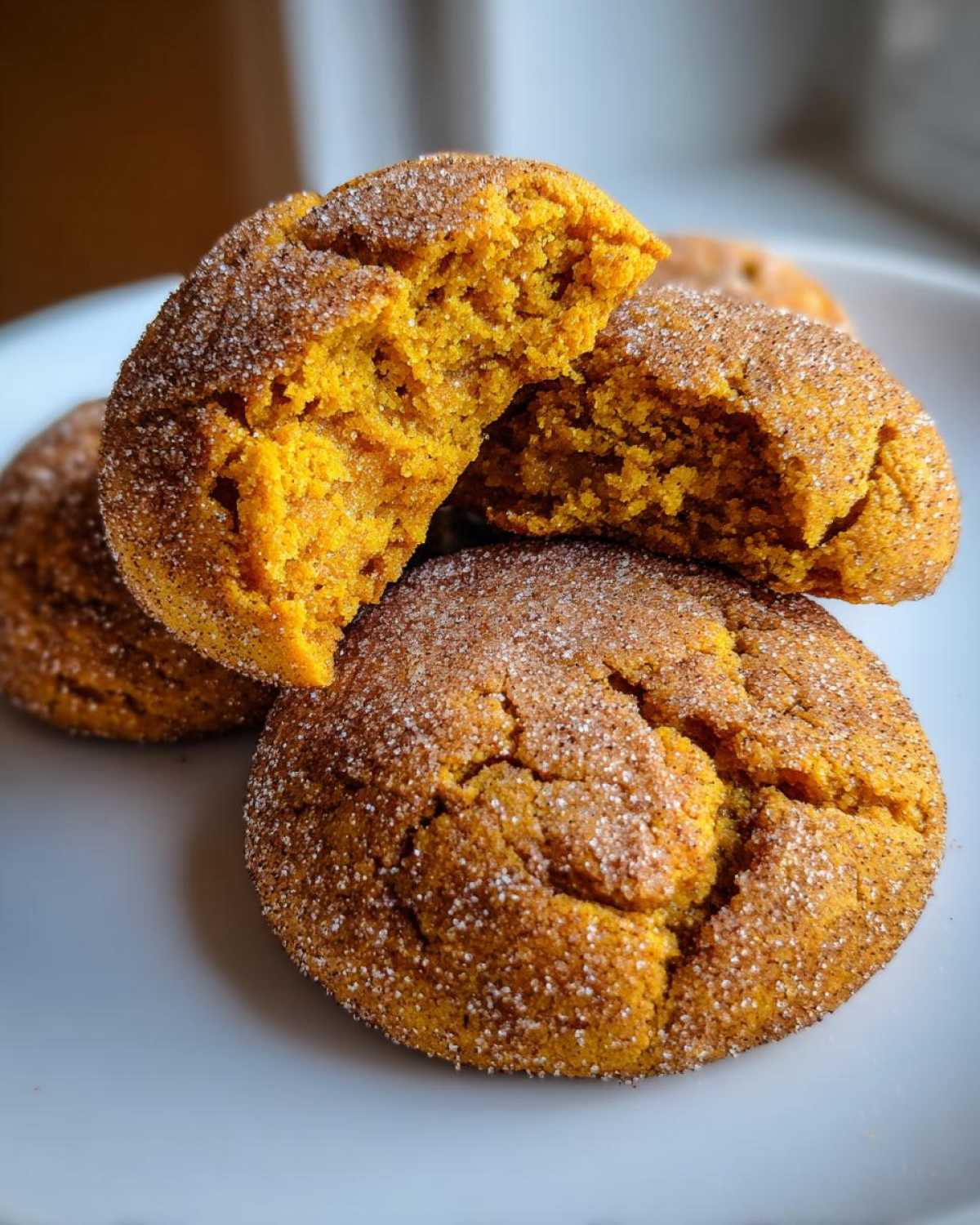 Close-up of chewy pumpkin snickerdoodle cookies rolled in cinnamon sugar, one cookie is broken open.