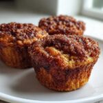 Close-up of three golden brown cinnamon sugar french toast muffins dusted generously with sparkling cinnamon sugar.