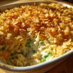 Close-up of creamy Tuna Casserole with egg noodles, peas, and a golden, crispy potato chip topping.