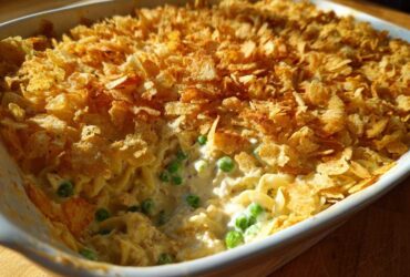 Close-up of creamy Tuna Casserole with egg noodles, peas, and a golden, crispy potato chip topping.