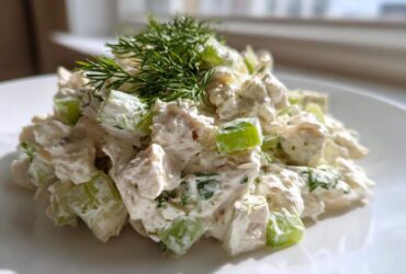 A mound of creamy cottage cheese chicken salad featuring chunks of white meat chicken and bright green celery, topped with fresh dill.