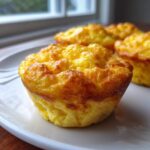 Close-up of a fluffy, golden-brown cottage cheese egg cups starbucks hack muffin on a white plate.