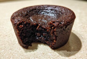 Close-up of a rich, dark chocolate Cottage Cheese Microwave Brownie with a bite taken out, showing a fudgy interior.