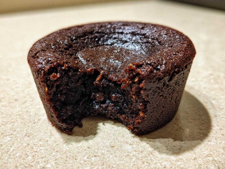 Close-up of a rich, dark chocolate Cottage Cheese Microwave Brownie with a bite taken out, showing a fudgy interior.