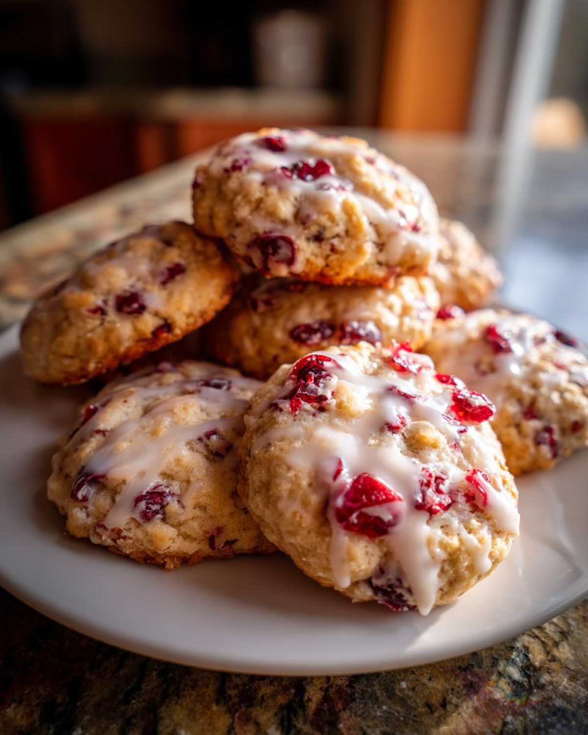 A stack of freshly baked cranberry orange cookies drizzled with a sweet white glaze, featuring visible dried cranberries.