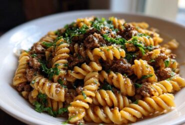 A close-up shot of a bowl of creamy beef pasta made with fusilli noodles and topped with fresh parsley.