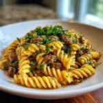 Close-up of a bowl of creamy beef pasta featuring rotini noodles, ground beef, and fresh parsley.